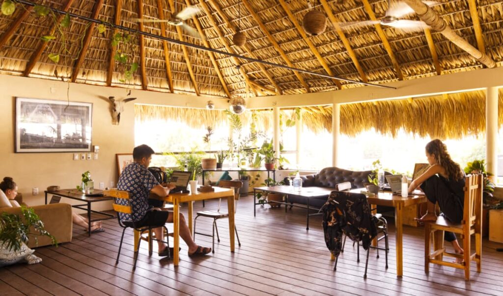 Travelers work on their laptops under the large palapa bar area at Puerto Dreams Hostel.
