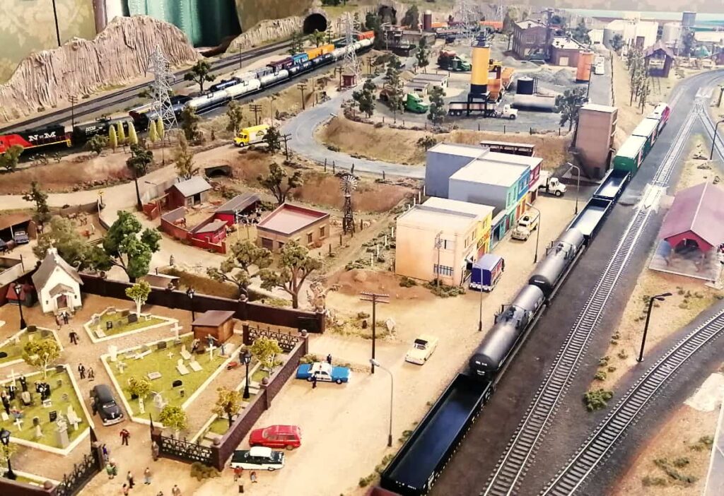 A church with funeral procession is the center of this image of the model train set that is house upstairs in the Train Museum, one of my favorite museums in Queretaro. Along the tracks, a train passes by the many other factors of life that are included in the model.
