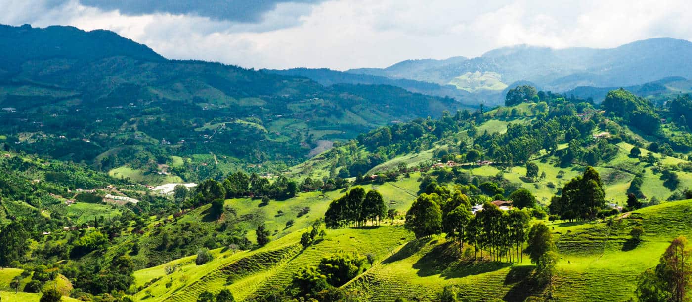 A landscape view of vibrant green rolling hills and mountain peaks surrounding Jerico, a day trip from Medellin