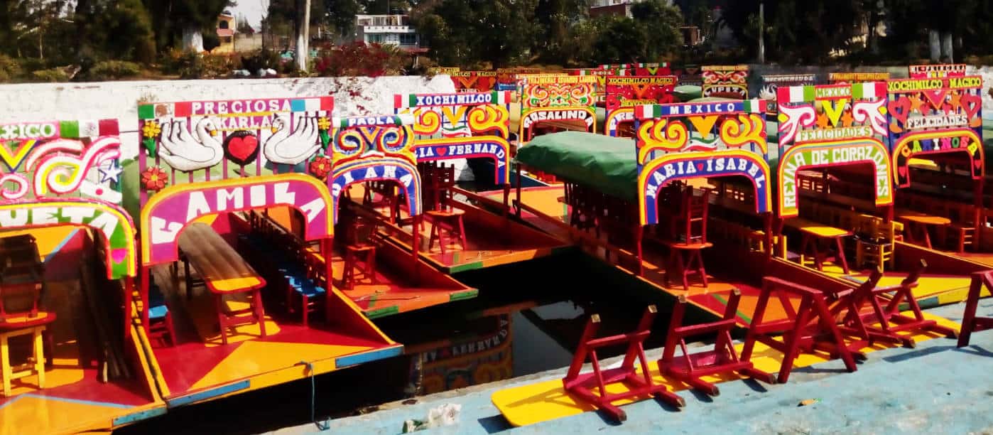Colorful boats lined up at Xochimilco, near Mexico City. Each boat is painted in vibrant colors and named.