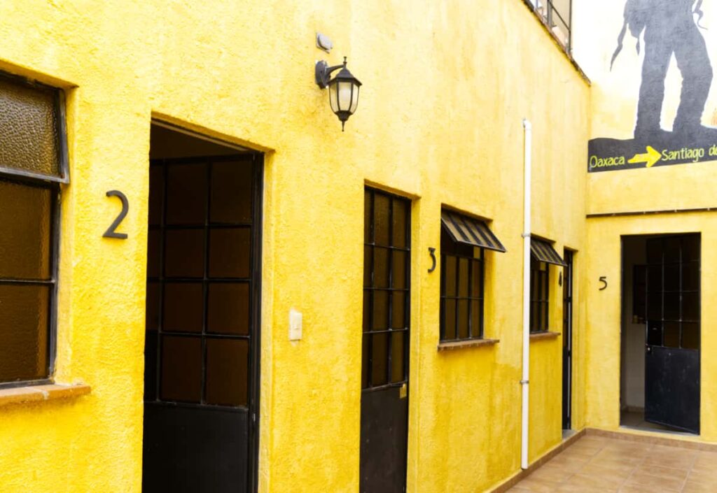 Four private rooms line the upper level of Andaina Hostel. The outside is painted a bright yellow.