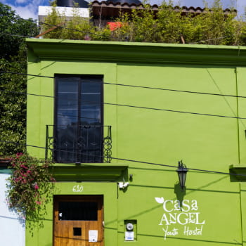 Square building painted bright green with white letters that read Casa Angel Youth Hostel.
