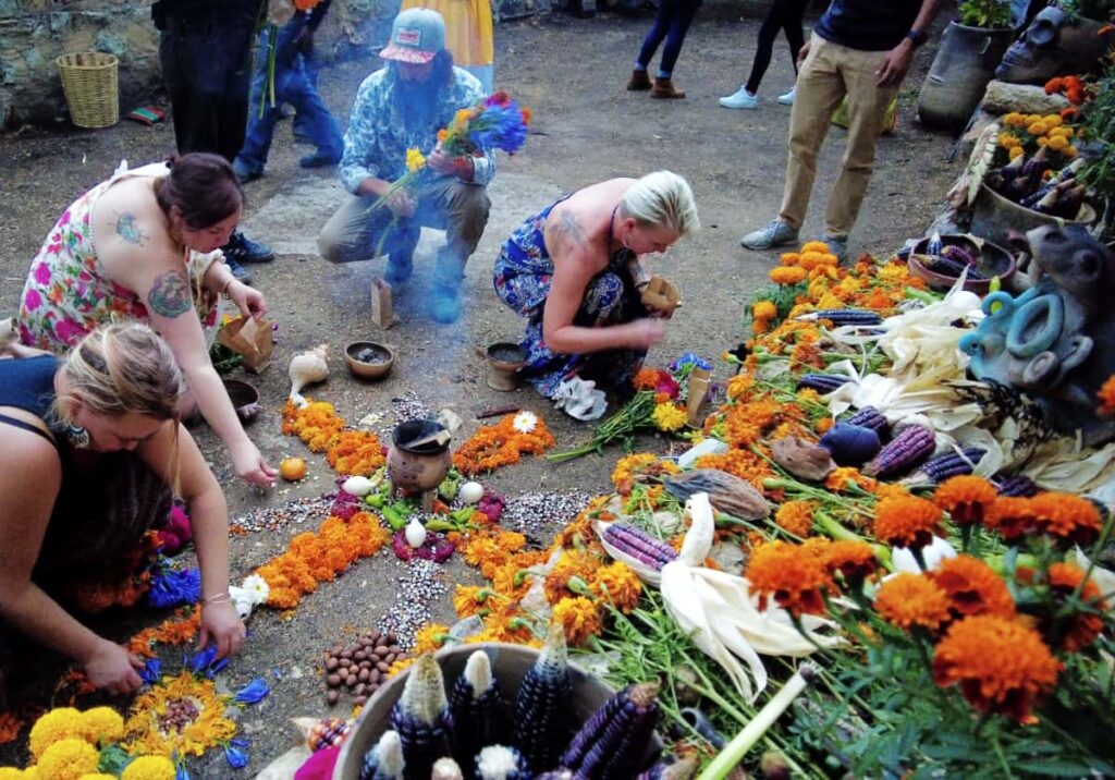 Guests on this dia de muertos experience make their contributions to the altar using maize, cacao, and colored flowers.