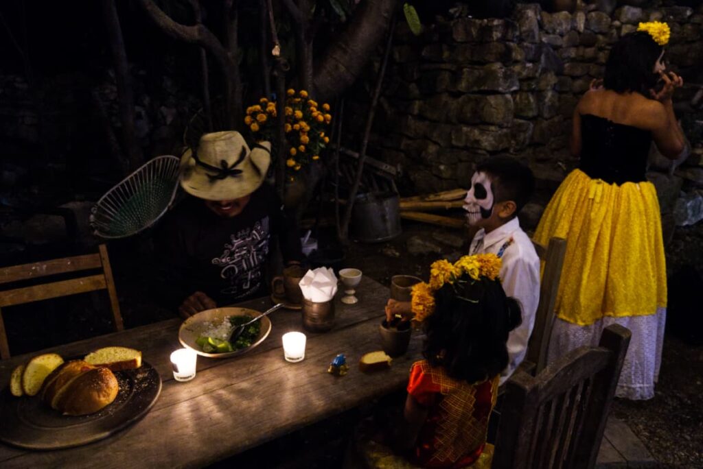 Carlos sits with his youngest children during Muertos Dinner. His son has his face painted and his daughter wears a headband of marigold flowers.