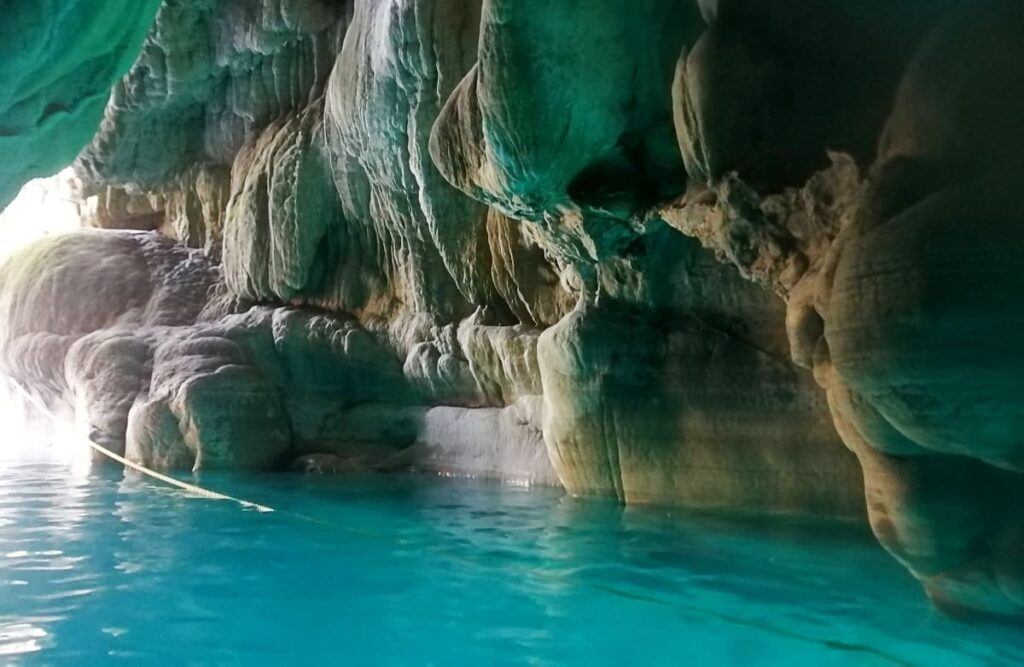 Sunlight illuminates the water at Puente de Dios in Tamasopo. The turquoise water is reflected on walls of the cave.