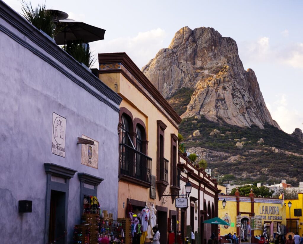 The large monolith of Pena de Bernal hovers over the small pueblo magico near Queretaro. In the foreground are colonial buildings. And in the background, the large, jagged monolith.