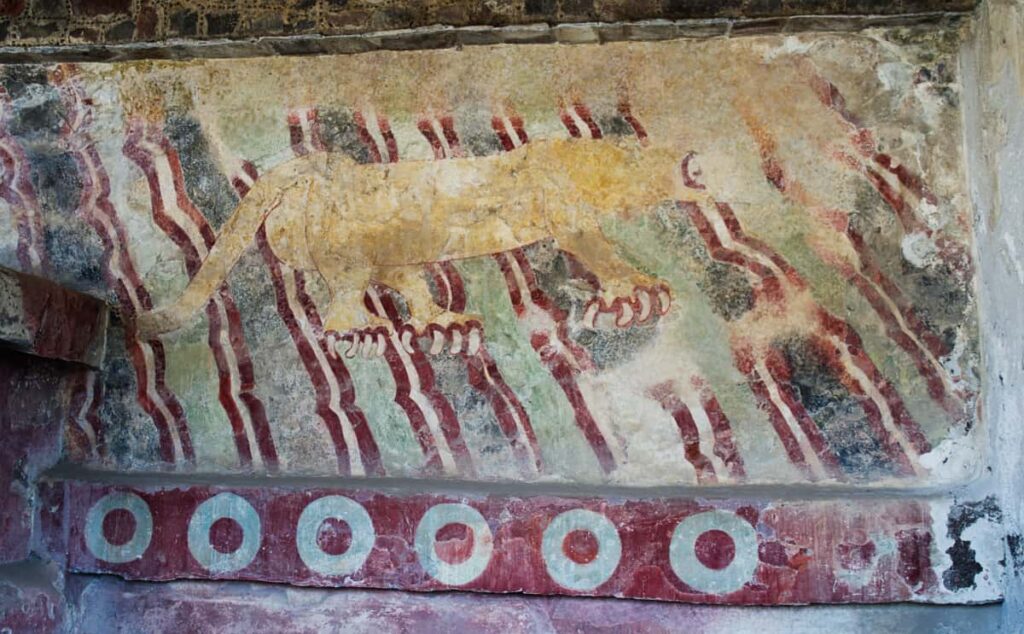 A mural painted on a stone wall at Teotihuacan depicts a puma with large claws and a thick tail. His head is no longer visible due to erosion. The mural includes abstract decorations in a strong red color.
