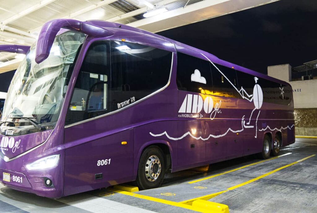 A dark purple luxury ADO bus is parked at a bus station in Mexico. ADO is one of the main Mexican bus companies.