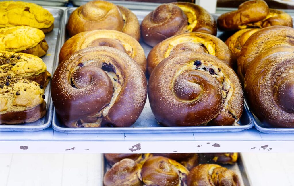 A specialty of Bernal, pan de queso is displayed in a glass case. This circular bread is swirled with cheese and fruit.