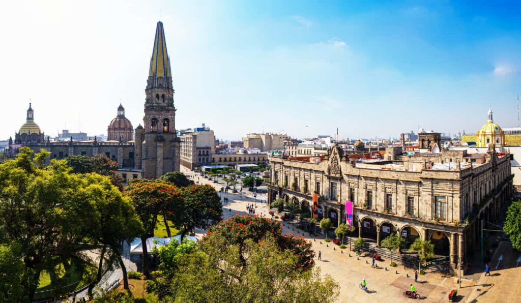 A street scene in one of the most popular cities in Mexico, Guadalajara. Large stone buildings and several church steeples can be scene in this overview photo.