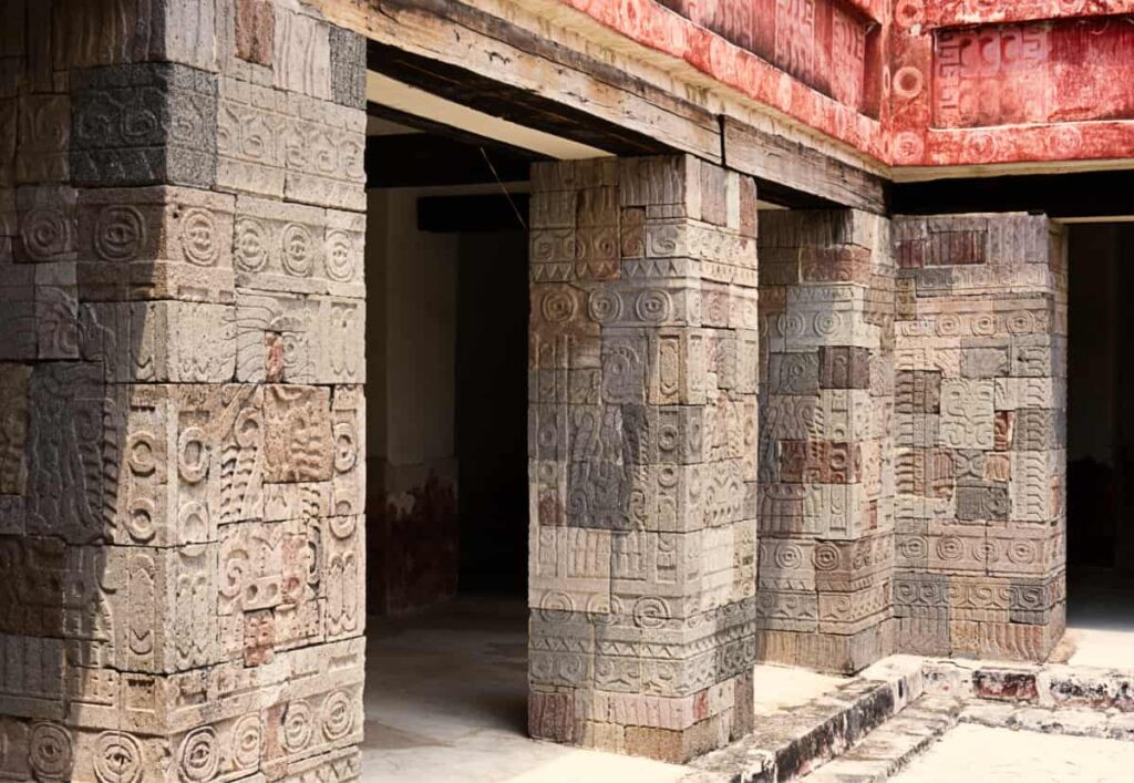 A close up of the stone carved columns inside the Palace of Quetzalpapalotl in Teotihuacan. The columns feature a human-bird figure and many prehispanic symbols.