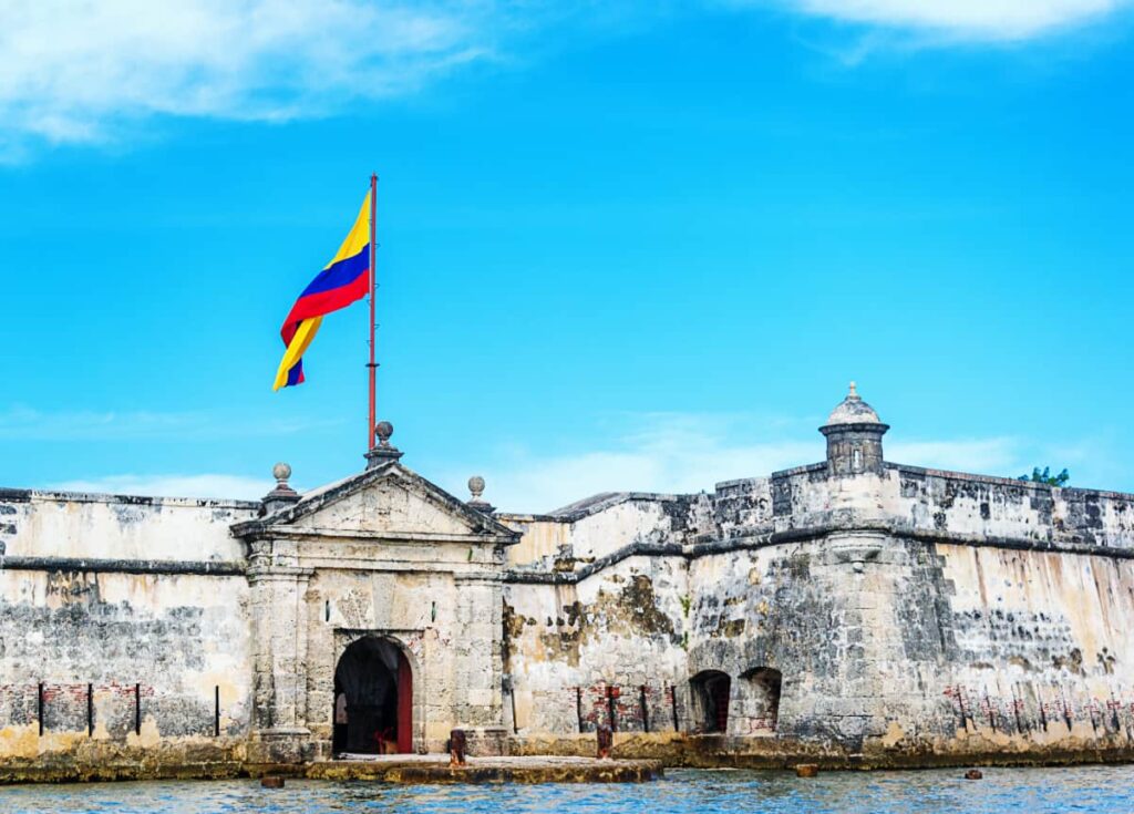 Outside view of the Bocachica Fort from a boat tour in Cartagena. The Colombian flag is flying above the entrance.
