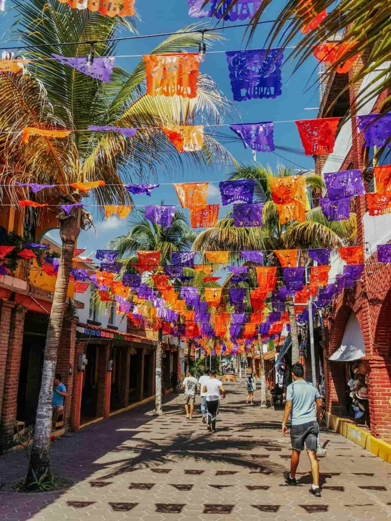 Vibrant downtown Zihuatanejo street decorated with papel picado. Pedestrians enjoying the safety of Zihuatanejo along a walking street.