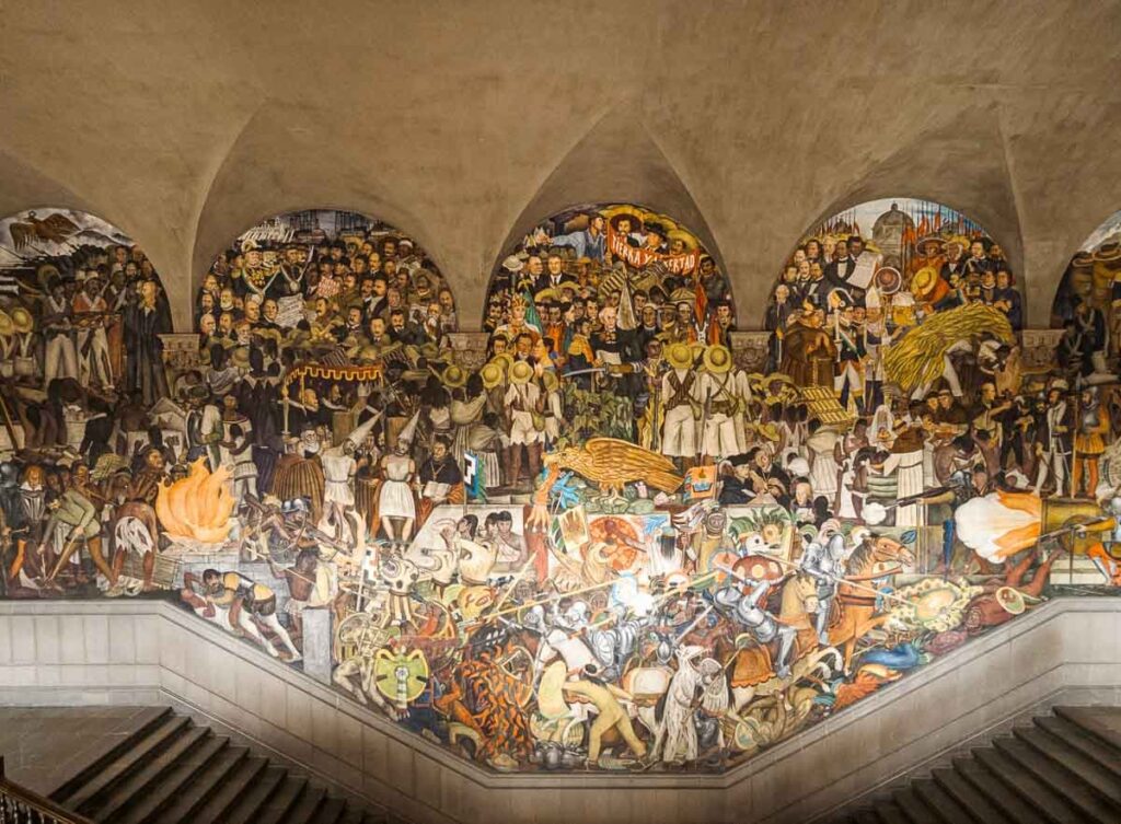 Diego Rivera mural in Mexico City painted on the wall showcasing the rich history of Mexico through vibrant depictions of ancient people and their cultural heritage.