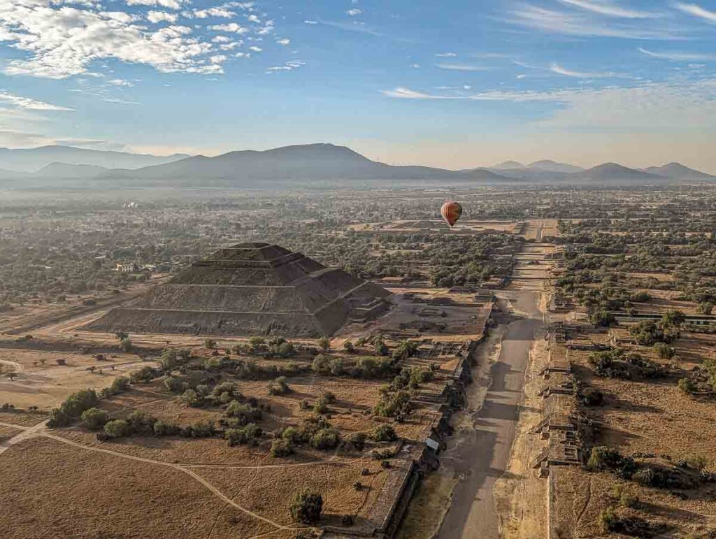 Hot air balloon drifting over the pyramid of Mexico City skyline.