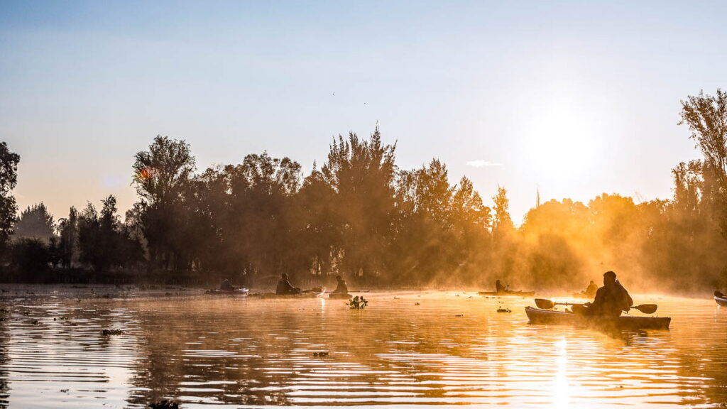 6 people kayaking in Xochimilco, Mexico during golden hour.