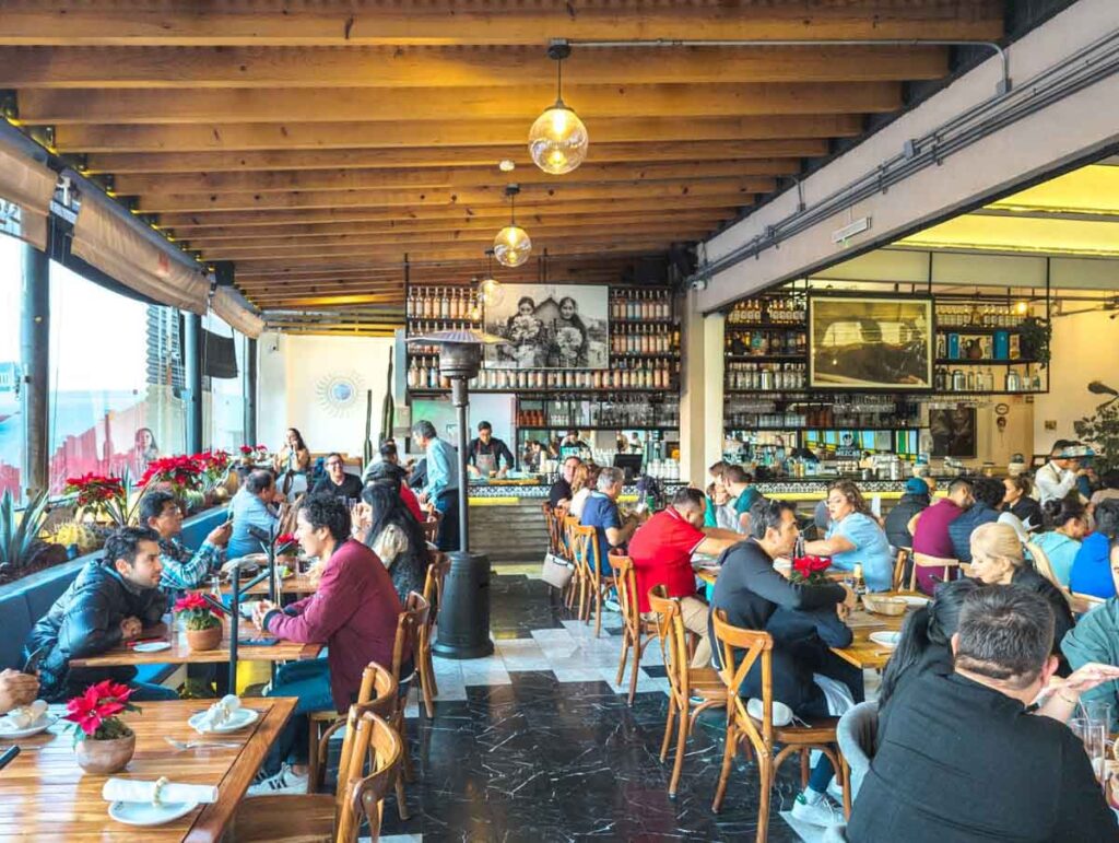 People dine at Terraza Cha Cha Cha - a rooftop restaurant in Mexico City with views of the Revolution Monument.