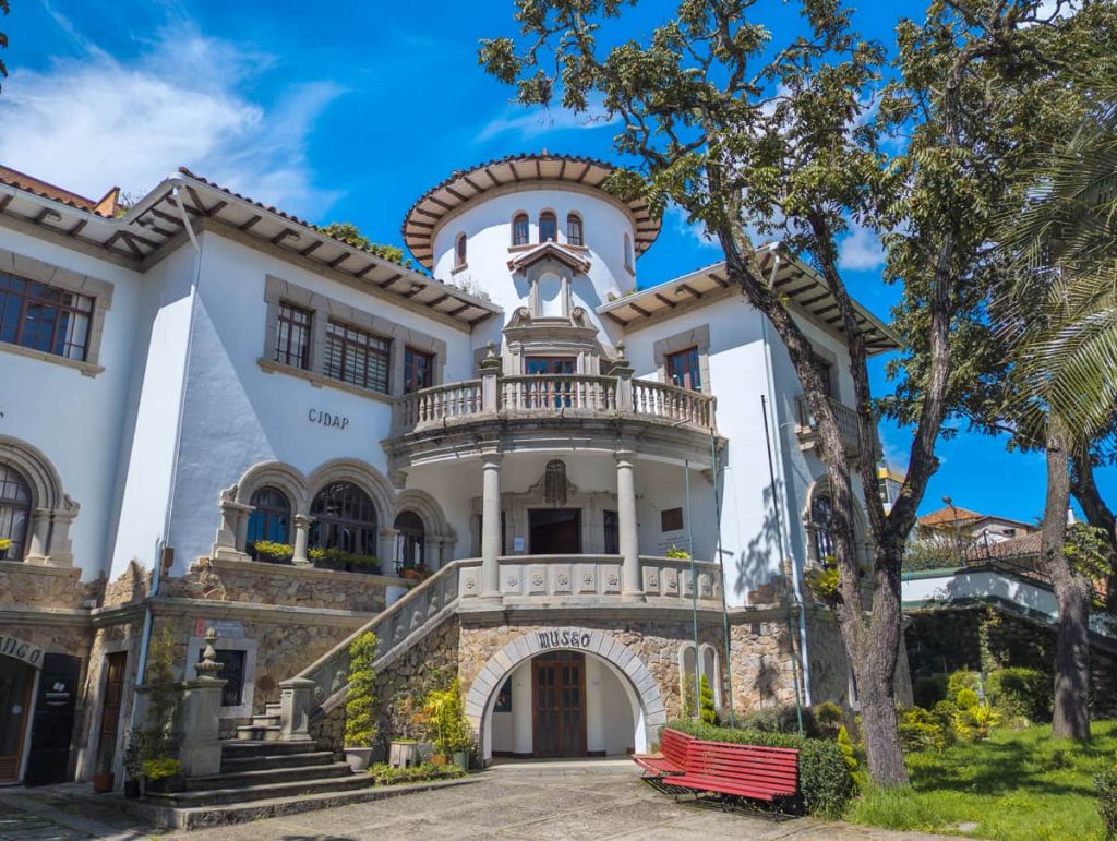 The grand exterior of CIDAP, the popular art museum in Cuenca Ecuador, showcasing its colonial architecture with arched balconies and lush garden space.