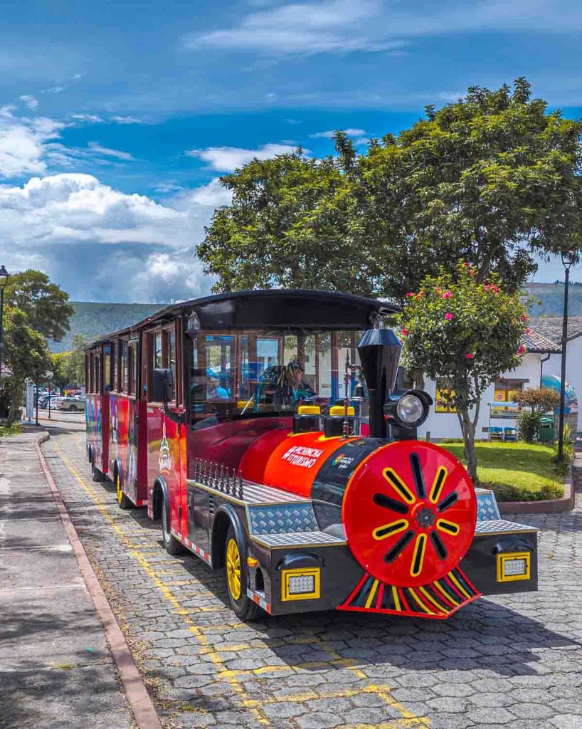 Bright red and yellow tourist train ready to transport visitors around Ciudad Mitad del Mundo near Quito Ecuador.