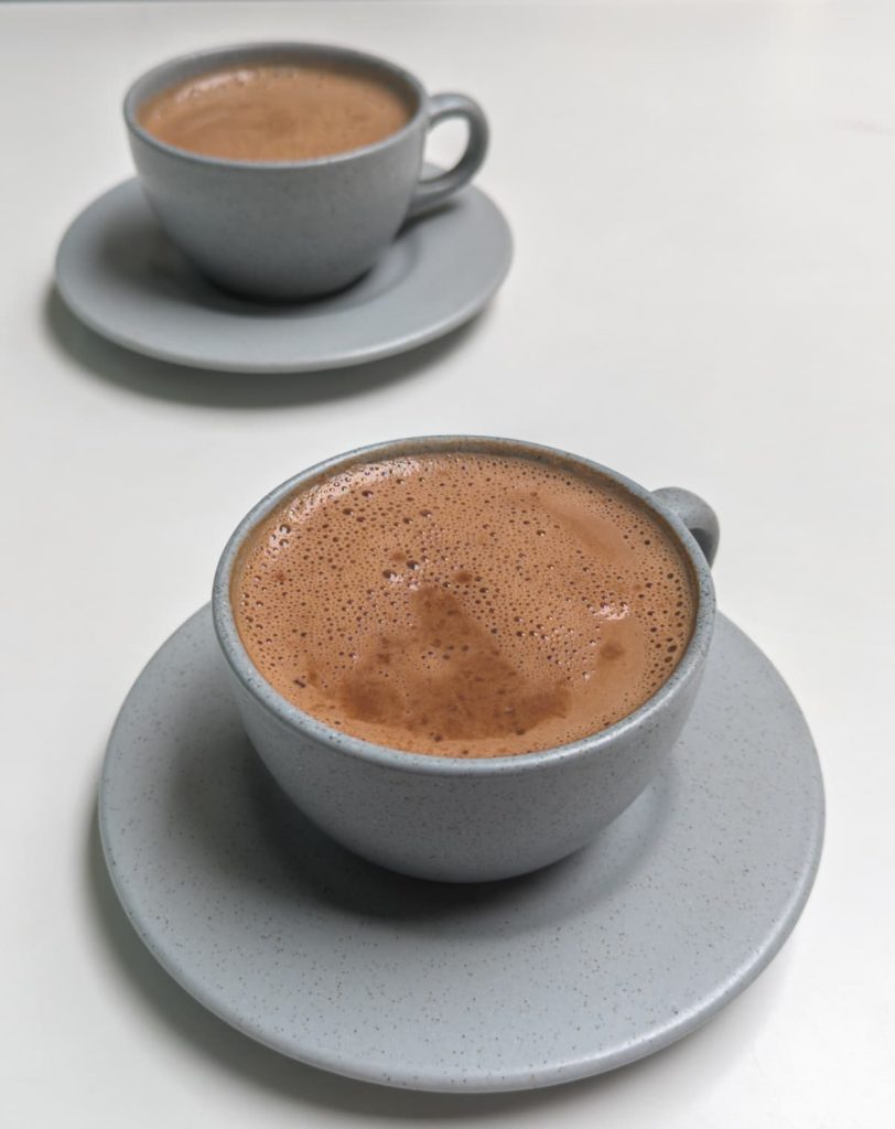 Two ceramic cups filled with rich, frothy hot chocolate served at Paccari chocolate shop in Cuenca Ecuador. Tasting Ecuadorian artisanal chocolate is one of the most delicious things to do in Cuenca.