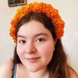 An up close portrait of Xochitl, a writer with extensive knowledge of Mexico for Cultures Traveled blog, wearing an orange marigold headband.