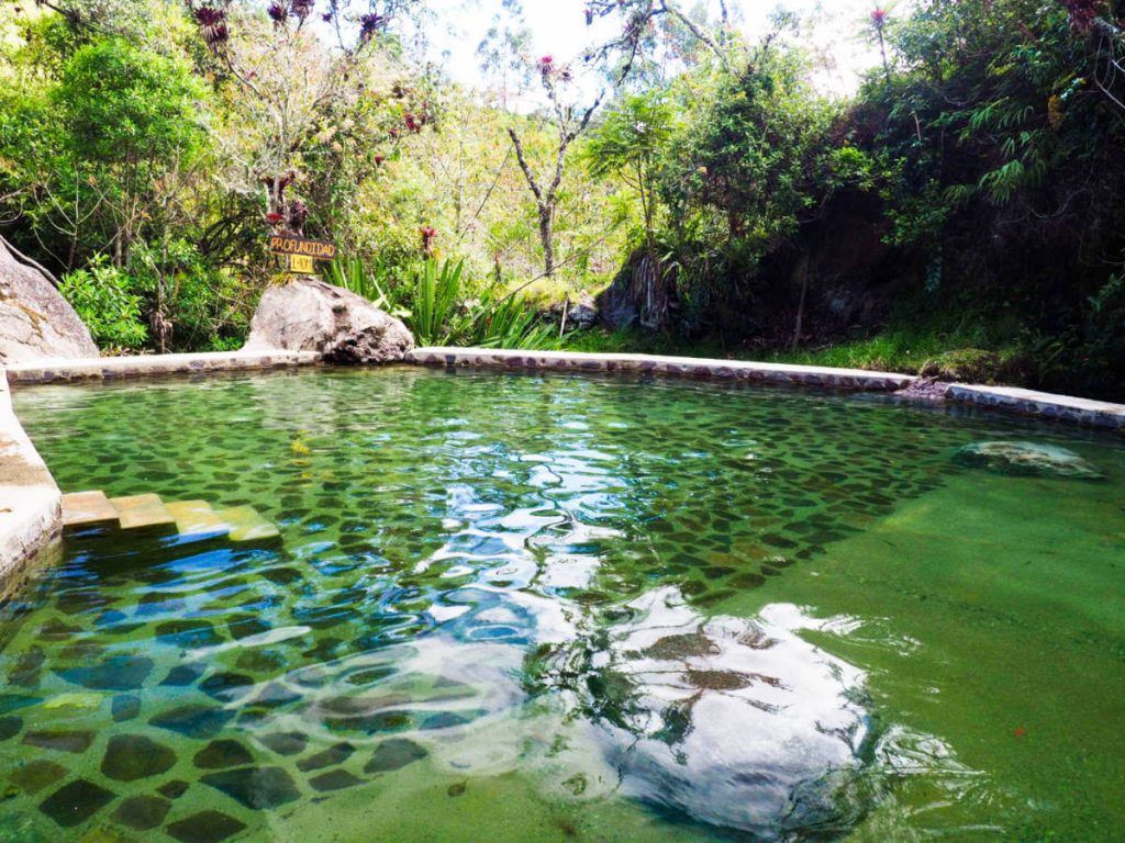 Large thermal pool with rock tiled bottom and surrounding trees at the Salinas hot spring in Coconuco