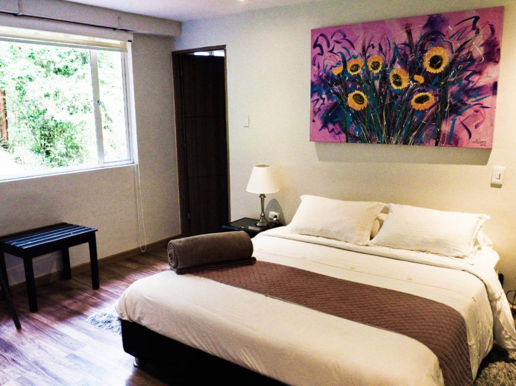 A queen size bed with modern furnishings and large windows at Los Volcanes
