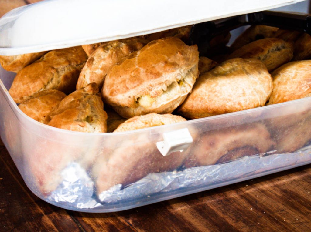 A plastic tupperware container filled with freshly baked empanadas. 