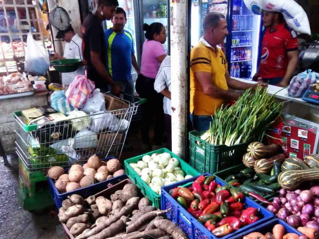 Vegetables displayed in plastic bins as people shop at the Bazurto Market in Cartagena.