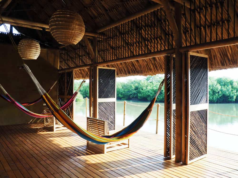 Hammocks hang under the palapa structure overlooking the mangrove lagoon.