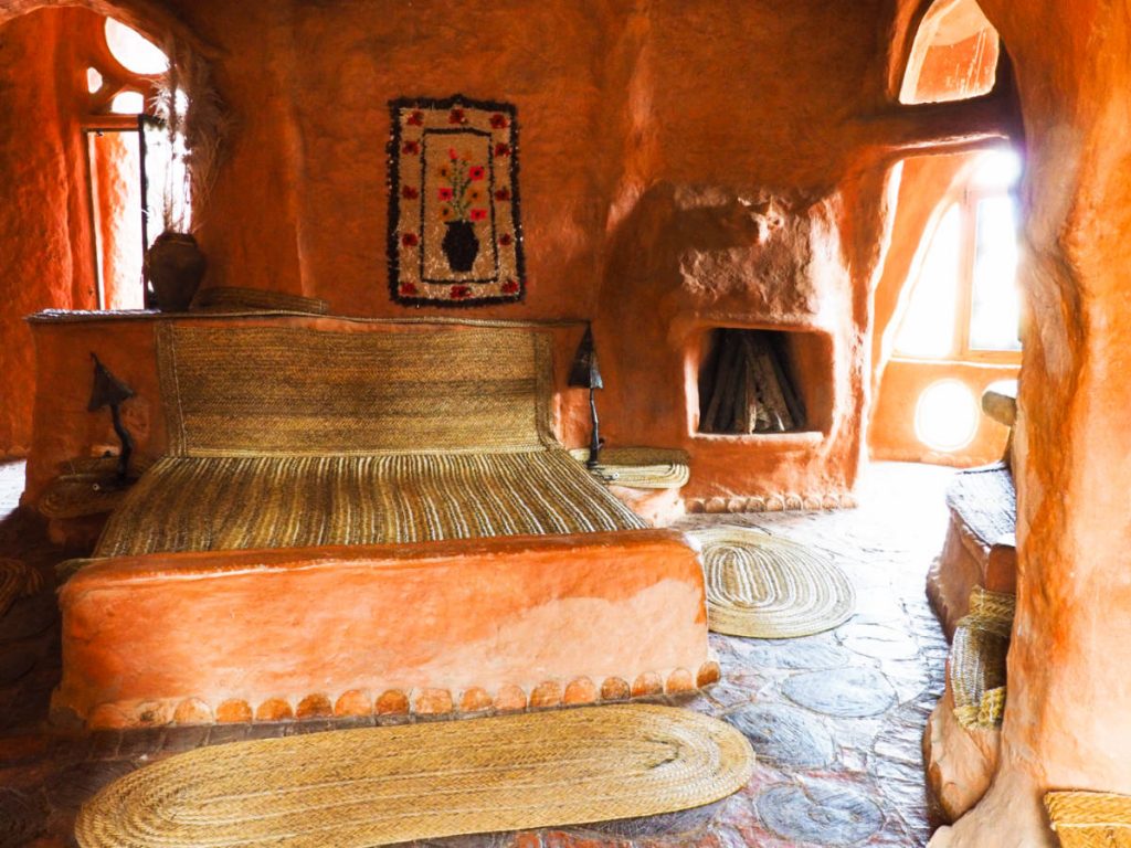 A bed frame and fireplace, both made of clay, in the master bedroom of Casa Terracota. Arched doorways and windows let light into the room.