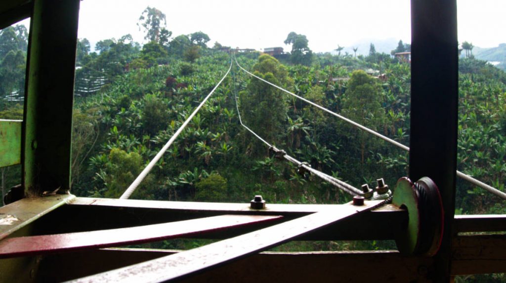 A view from inside the cable car looking out over the cables and banana field below