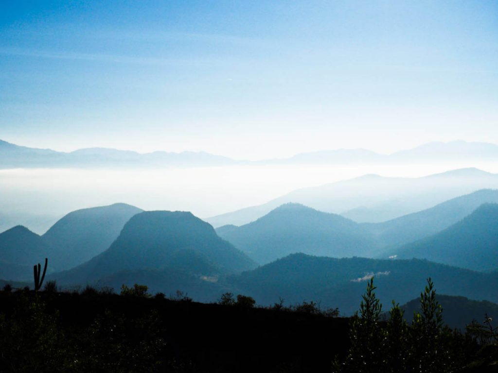 Sun filters through the mountains and the valley below Hierve el Agua in Oaxaca