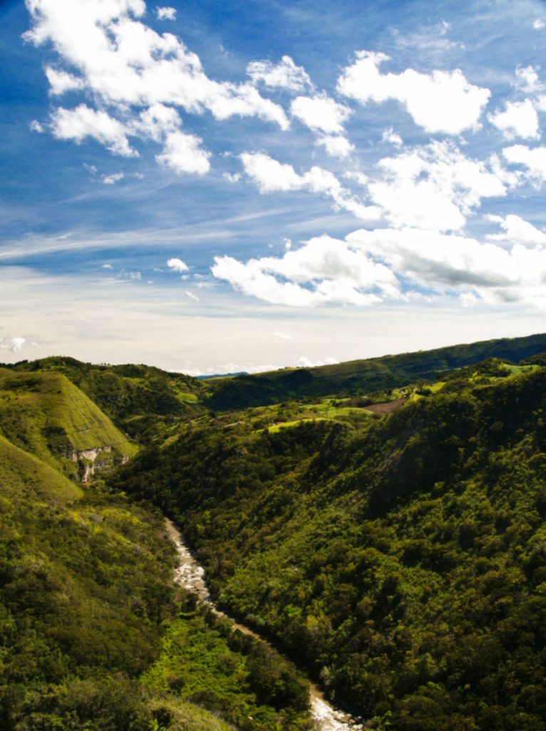 A small river passes through the low green mountains that cut through the landscape near Paso del Angel.
