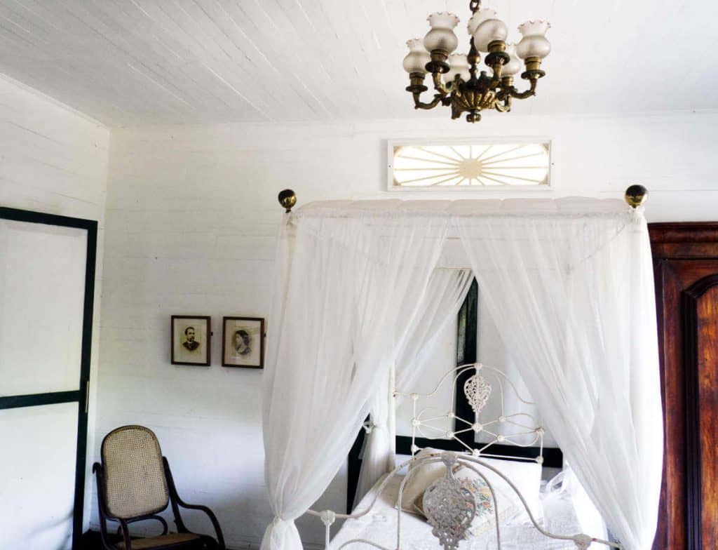A canopy bed draped in white located in a bedroom at the House of Rafael Nunez.