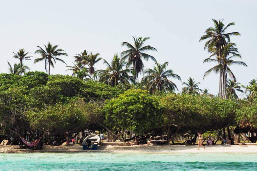 From the boat, a view of the side of the island with places to stay in Isla Mucura with tall palms in the background.