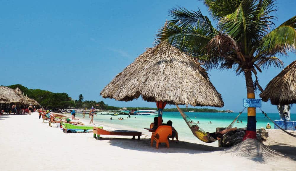 During a stop to Tintipan, a man enjoys a siesta in a shaded hammock hanging between a palapa and palm tree.