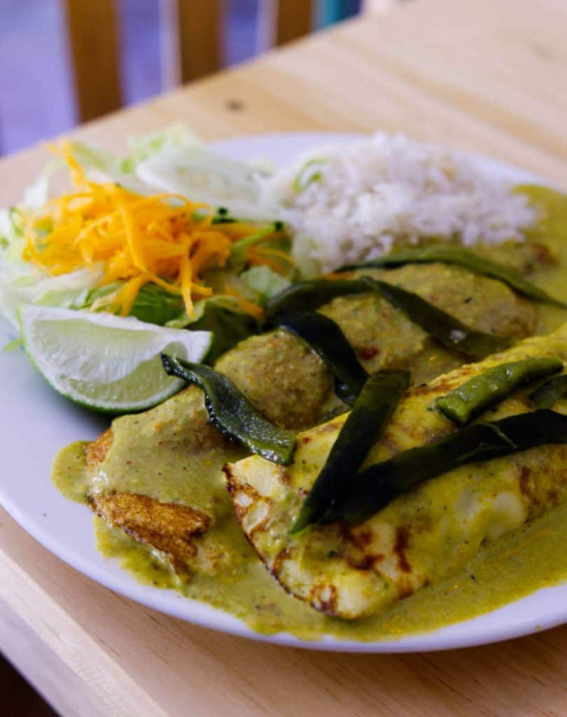 A plate of chicken crepes topped with sliced poblano peppers and smothered in a creamy poblano sauce at La Cocina, one of many great San Cristobal restaurants. Accompanied by white rice and a small side salad.
