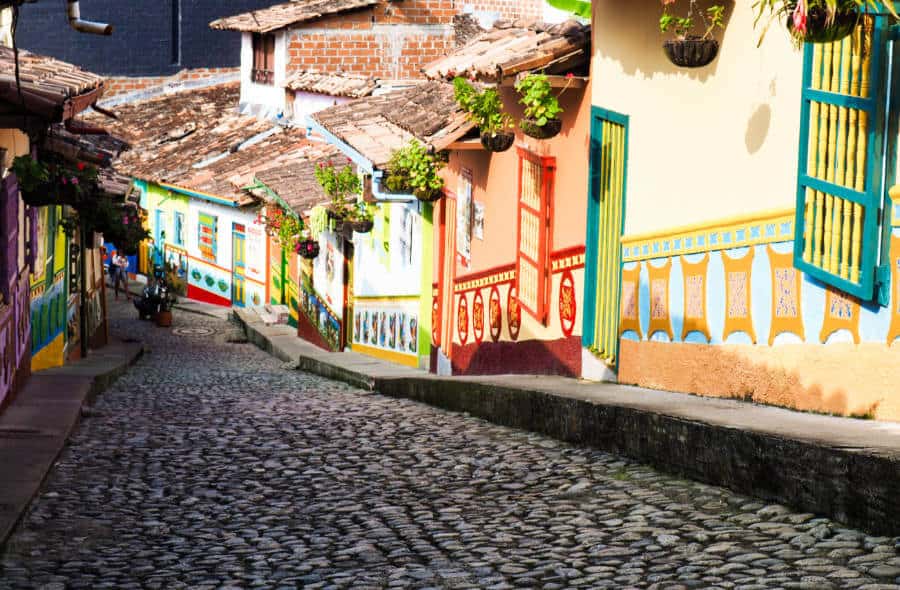 A cobblestone street, void of cars, with colorful houses lining the sides in Guatape, Colombia.