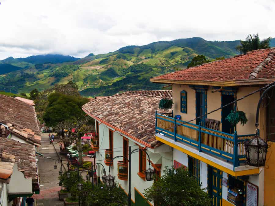 Looking down past the colorful houses to the street of Jerico with bright green mountains in the background.