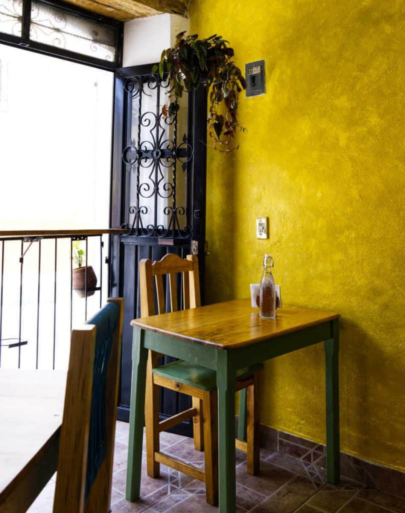 At one San Cristobal restaurant, simple wooden tables and chairs line the brightly painted yellow walls with adorning plants and window open to the outside.