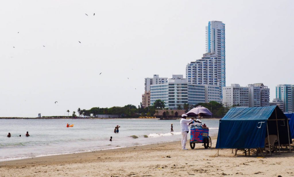 At Castillogrande, one of the beaches near Cartagena, a vendor sells ceviche from his cart to people lounging under tents while others play in the ocean.