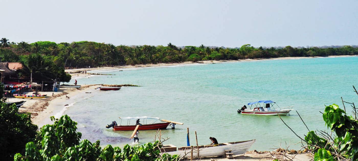 In one of the bays in Rincon del Mar, men load boats with wood and other materials.