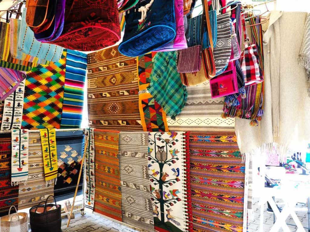 Colorful woven blankets, tapestries, and bags hang in the Tlacolula Market near Oaxaca.