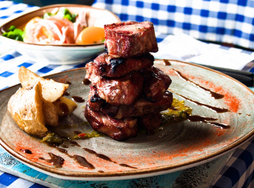 Short ribs stacked on top of each other with a side of potatoes and in the background a side salad in a bowl at one of the best restaurants in Villa de Leyva.