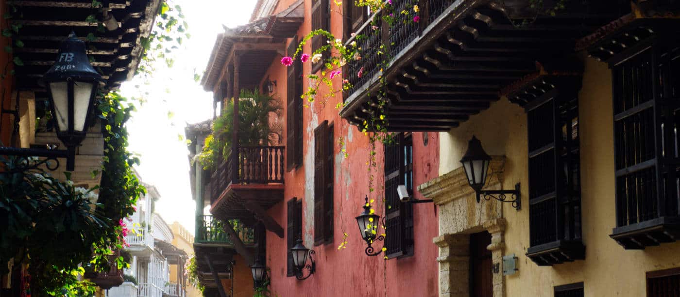 Colorful street view of homes in Cartagena with tropical plants spilling over the balconies and gas lanterns