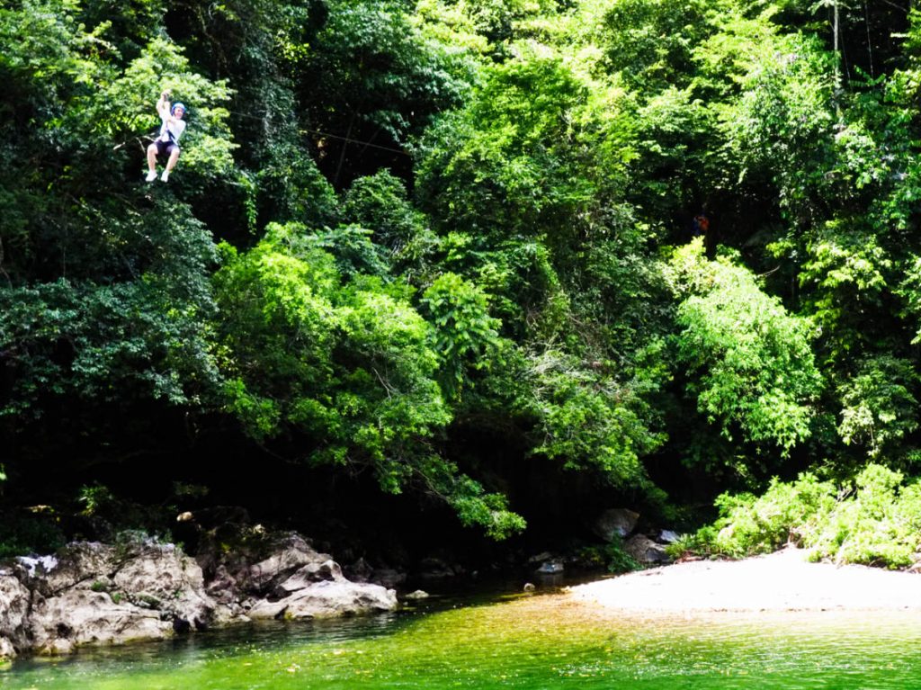 A young boy zip lines through the canopy and over the river at Playa Marmol.